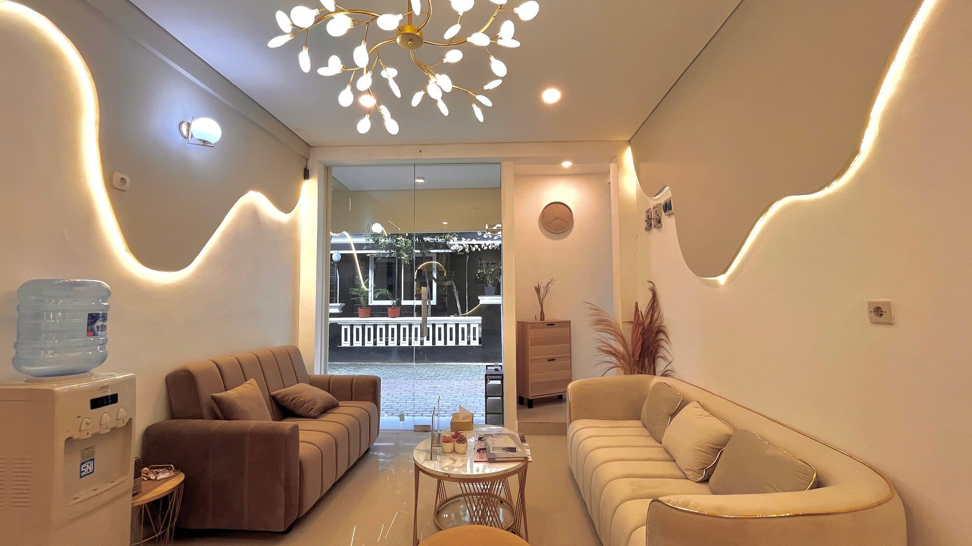 Ruang tunggu dengan sofa dan pintu kaca menghadap taman
